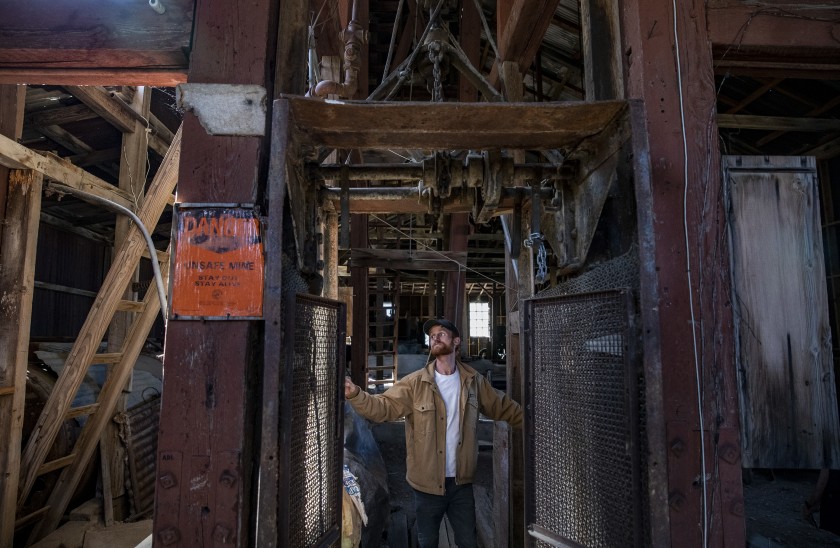 Brett Underwood stands between massive wooden posts of the headframe of the Union Mine in Cerro Gordo ghost town