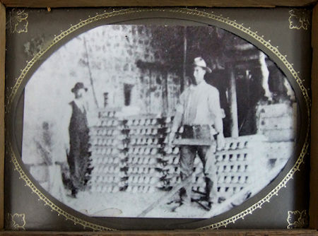 Workers display the 18-inch-long, 85-pound silver-lead ingots that were shipped by wagon from the Cerro Gordo mines to Los Angeles. Photograph hangs on a wall inside the Belshaw House Workers display the 18-inch-long, 85-pound silver-lead ingots that were shipped by wagon from the Cerro Gordo mines to Los Angeles. Photograph hangs on a wall inside the Belshaw House