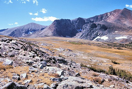 This is the view southeast across Parker Pass. The rounded gray peak on the left is Parker Peak. The depression in front of the black mountain is occupied by Parker Pass Lake This is the view southeast across Parker Pass. The rounded gray peak on the left is Parker Peak. The depression in front of the black mountain is occupied by Parker Pass Lake
