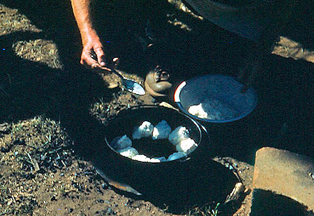 'Doc' Loomis placing bisquits in Dutch Oven at Zastro Camp 'Doc' Loomis placing bisquits in Dutch Oven at Zastro Camp
