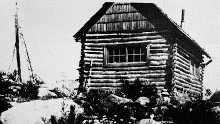 A log cabin with a pole to climb like a ship’s mast to check for fires, served as the Buck Mountain Lookout in 1923